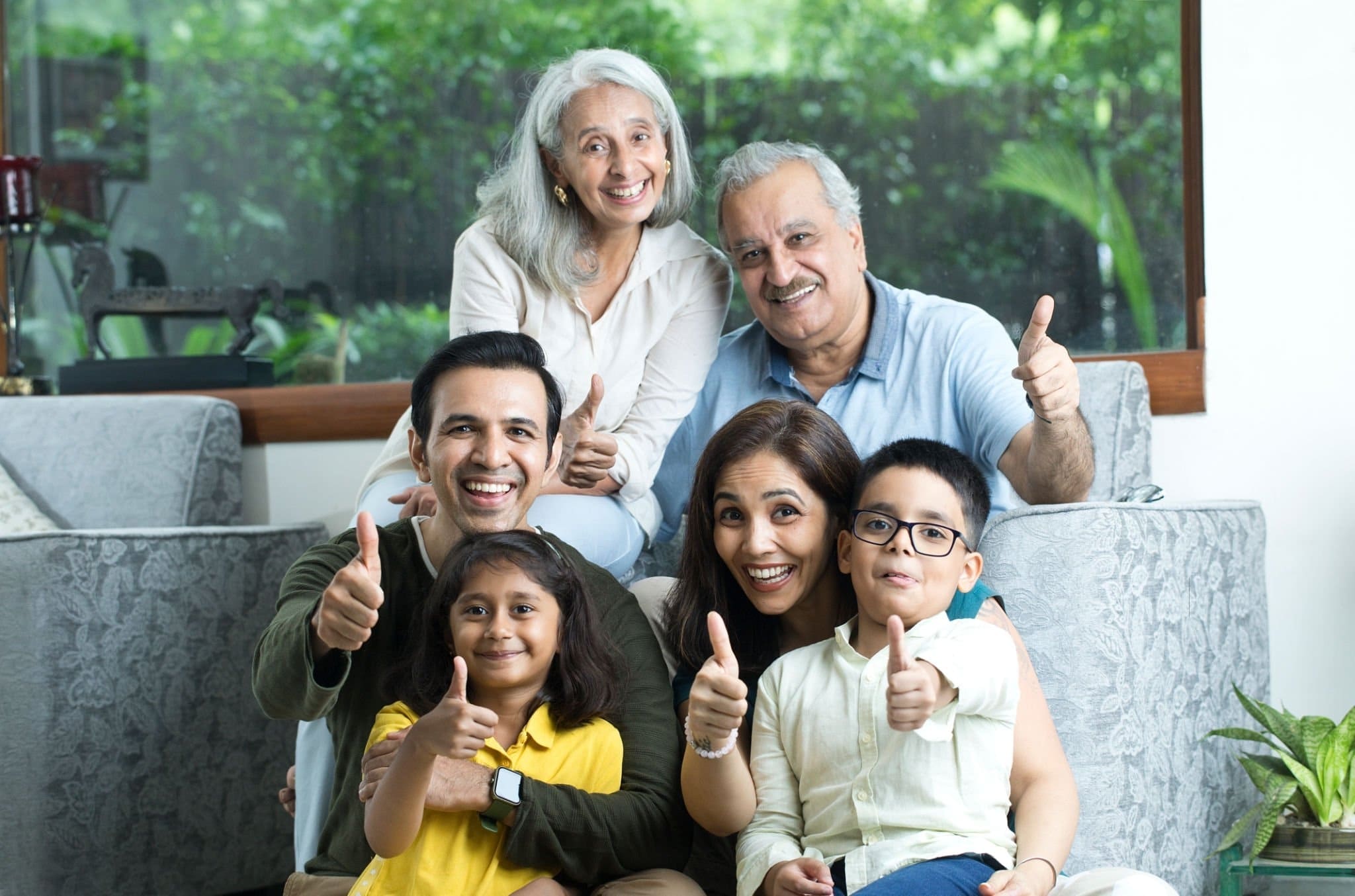 A happy multigenerational Indian family smiling and giving thumbs up, showcasing great digestive health and wellness under the care of the best gastroenterologist in Delhi.